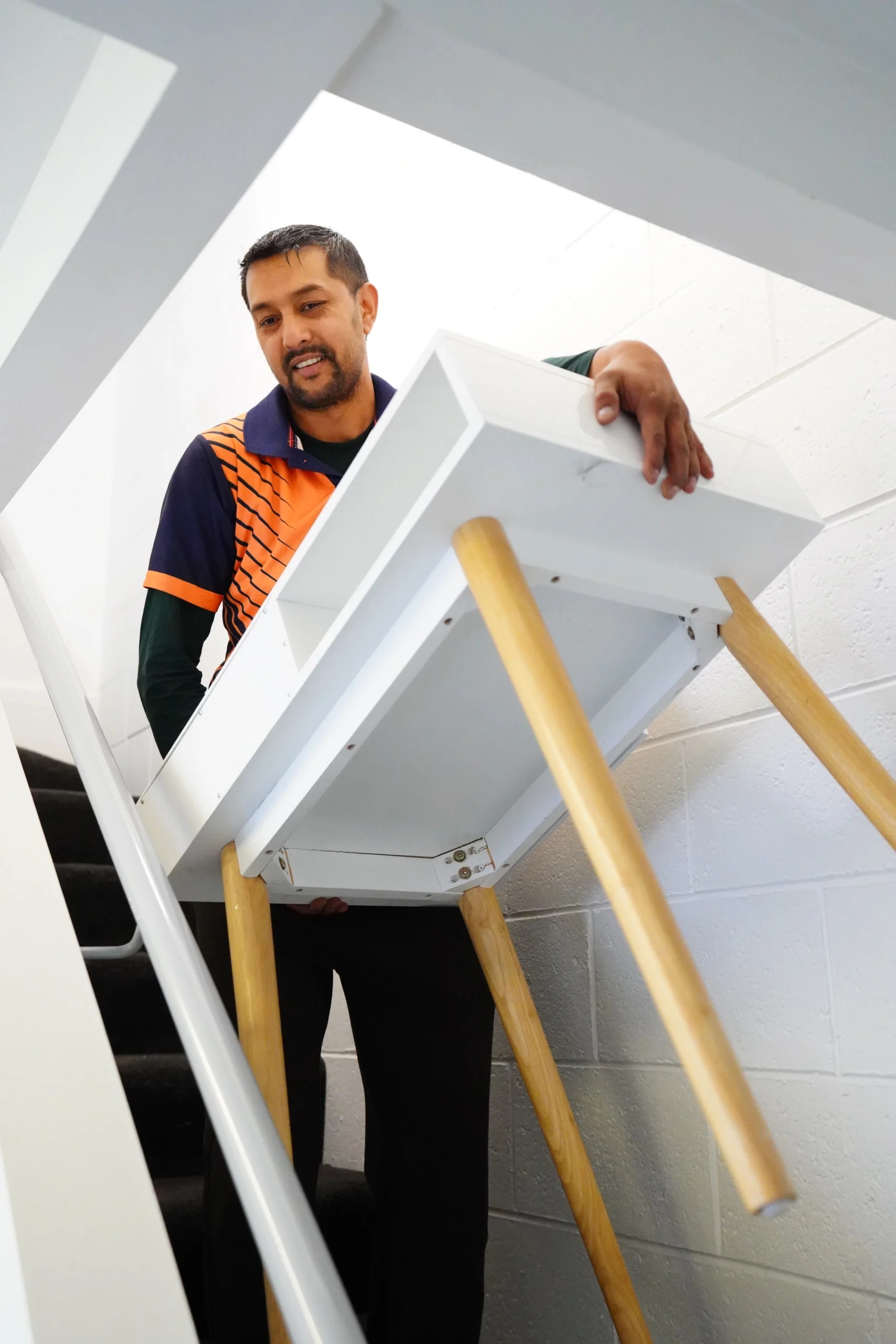 Furniture movers in Christchurch carefully carrying a table during a safe furniture moving service