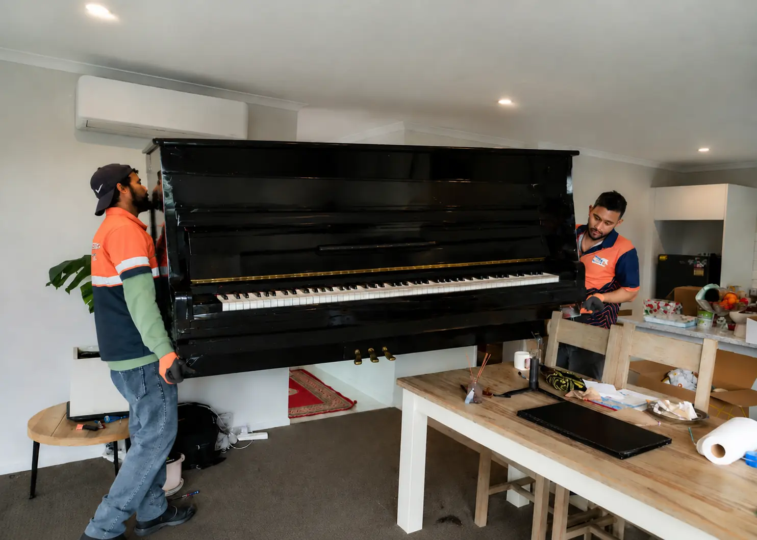 Professional movers in Christchurch carefully moving a piano during a residential relocation